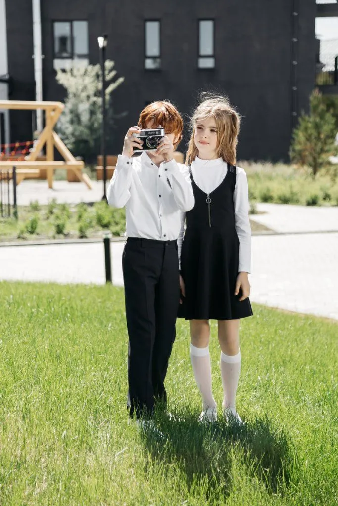 На мальчике: Трикотажная сорочка SH21J003-SL; брюки TR21B002-312. На девочке: Сарафан SK21G104, водолазка JKN21G001